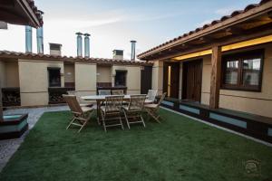 un patio con una mesa y sillas en el césped en Apartamentos Turísticos La Panadería de Flora, en Martiherrero