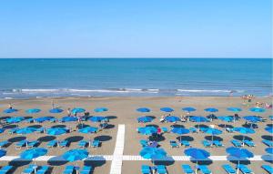 Nice Home In Tarquinia With Outdoor Swimming Pool في Porto Clementino: شاطئ فيه مظلات زرقاء وناس على الشاطئ +13 صورة