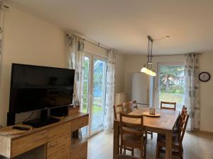 unter den Kiefern 99 في Marienfelde: غرفة طعام مع تلفزيون وطاولة مع كراسي