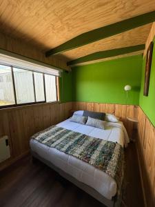 Cama en habitación con pared verde en Refugio Zarapito View of the Pudeto River, en Pudeto