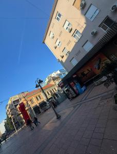 a couple of people walking down a sidewalk next to buildings at SpaNish FoROOM 1 in Niš
