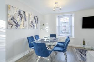 a dining room with a glass table and blue chairs at Casa Fresa - 224 King St in Broughty Ferry