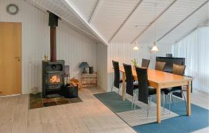 4 Bedroom Gorgeous Home In Tranekær في Stoense: غرفة طعام مع طاولة وموقد خشبي