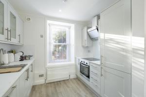 a white kitchen with white cabinets and a window at Casa Fresa - 224 King St in Broughty Ferry
