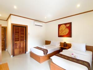 a hotel room with two beds and a door at Na Soi 5 Chiangkhan in Chiang Khan