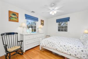 a bedroom with a bed and a chair and windows at 350 School House Road Eastham - Beach Dreams in Eastham