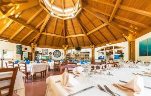 Lovely Home In Tarquinia With Swimming Pool في Porto Clementino: مطعم بطاولات بيضاء وكراسي وسقف كبير