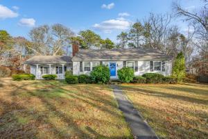 a white house with a blue door on a yard at 350 School House Road Eastham - Beach Dreams in Eastham