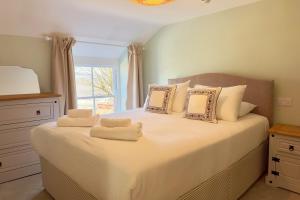 una camera da letto con un grande letto bianco con cuscini e una finestra di The Little Egret a Swansea