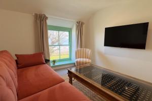 un soggiorno con divano e TV a schermo piatto di The Little Egret a Swansea