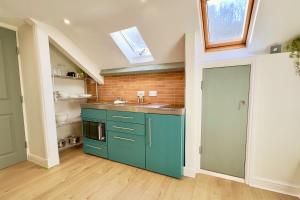 una cucina con armadi blu e un muro di mattoni di The Little Egret a Swansea