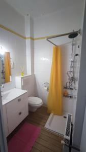 a bathroom with a toilet and a yellow shower curtain at Chambre Luxurieux Gris in Perpignan