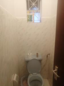 a small bathroom with a toilet with a window at Mirema palace in Nairobi