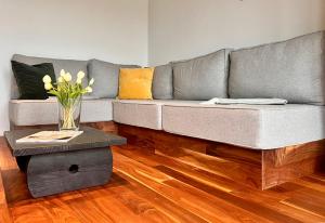 a grey couch with a vase of flowers on a table at Wildwald Lodge in Döbrönte