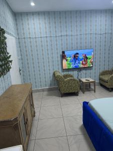 コナクリにあるHôtel Africa Pas Chersの壁にテレビが取り付けられたリビングルーム