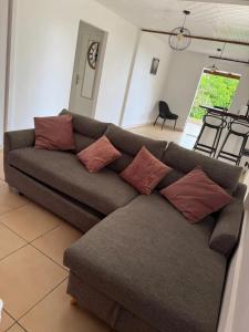 a couch with pillows sitting in a living room at Villa avec piscine privée à Rivière-Salée - 110 m² in Quartier la Fleury Guiné +8 photos