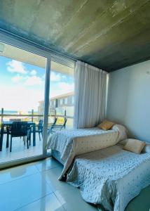 two beds in a room with a view of a balcony at Apart Spa Linda Bay in Mar de las Pampas