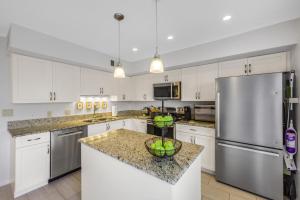 a kitchen with white cabinets and a stainless steel refrigerator at San Marco Villas S-7 in Marco Island