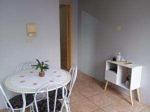 un tavolo bianco e sedie con una pianta in vaso sopra di Apto confortável com Churrasqueira 03 a Cachoeira do Sul Altre 4 foto