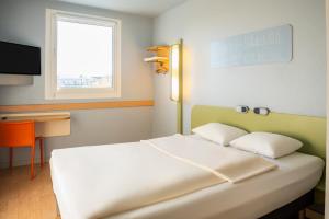 a bedroom with a white bed and a window at ibis budget Muenchen Ost Messe in Aschheim +66 photos
