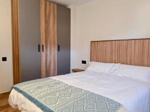 ein Schlafzimmer mit einem großen weißen Bett mit einem hölzernen Kopfteil in der Unterkunft Apartamentos Casa Domec in Castejón de Sos