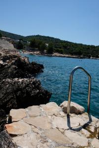 een metalen reling op rotsen naast een wateroppervlak bij House Robinson house in Dolac