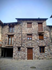 ein altes Steingebäude mit einer Holztür in der Unterkunft Apartamentos Casa Domec in Castejón de Sos