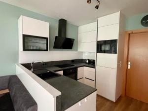 Una cocina con gabinetes blancos y una encimera negra. en Residenz Monica Top 2, en Sankt Margarethen 16 fotos más
