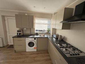 a kitchen with a washer and a sink and a washing machine at Livs cozy corner in Crossens
