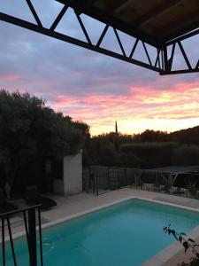 a swimming pool with a sunset in the background at La Corentine in Bandol