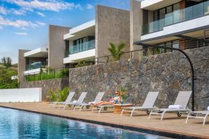 a woman sitting on a chair next to a swimming pool at Domaine d'Anbalaba in Ruisseau Créole