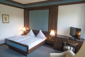 a bedroom with a bed and a desk with a television at Landhaus Deuber in Weismain +3 photos