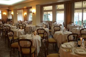 a dining room with tables and chairs with white linens at Hotel Villa Bianca Resort in Taormina