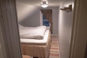 Una pequeña habitación con una cama y una ventana. en Beautiful little house which offers the best of Senja, en Gibostad