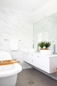 a white bathroom with two sinks and a mirror at Oceans 21 Caves Beach in Caves Beach