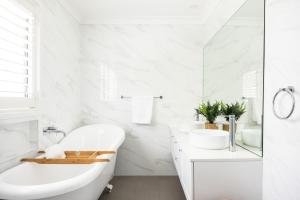 a white bathroom with a tub and a sink at Oceans 21 Caves Beach in Caves Beach +49 photos