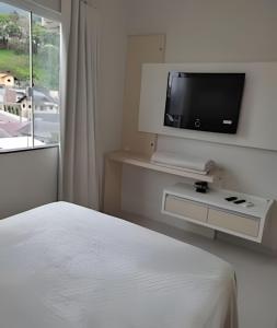una camera da letto con un letto e una TV a schermo piatto di Apartamento Harmonia 402 a Pomerode
