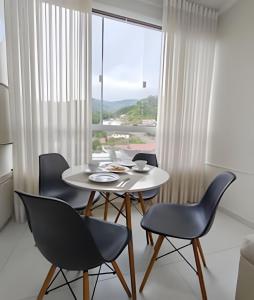 una sala da pranzo con tavolo, sedie e una finestra di Apartamento Harmonia 402 a Pomerode