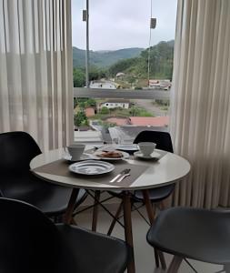 un tavolo e delle sedie con un tavolo e una finestra di Apartamento Harmonia 402 a Pomerode