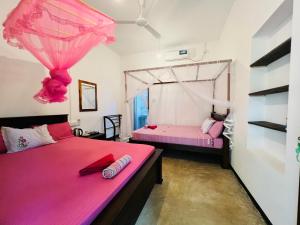 two beds in a room with pink sheets at Ancient Tree in Mirissa