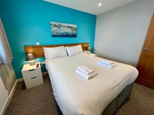 una camera da letto con un grande letto bianco con pareti blu di Seaside Escape in Westward Ho! 3-Bed Family Holiday Home with Sea Views a Westward Ho