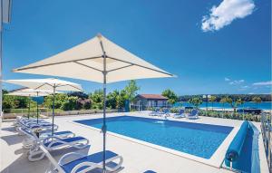 una piscina con sedie e ombrelloni di 2 Bedroom Awesome Apartment In Punat a Punat Altre 9 foto