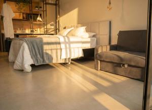 a bedroom with a bed and a couch and a chair at Pousada Austral Suítes in Imbituba