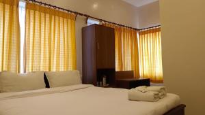 Un dormitorio con una gran cama blanca con cortinas amarillas. en LMS Palve Sugavasam, en Ooty