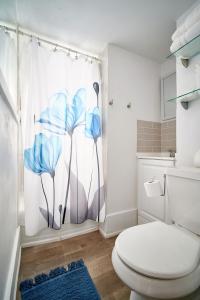 a bathroom with a toilet and a shower curtain with blue flowers at Capitol-Side • Downtown • Attic Harry-Potter Door in Cheyenne +20 photos