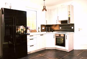 a kitchen with white cabinets and a black refrigerator at Seestern in Neuenkirchen auf Rugen