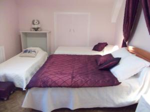 2 letti in una camera con viola e bianco di Le Logis Des Grenouilles B&B a Morieux