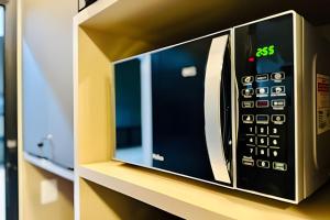 a microwave oven sitting on top of a shelf at Studio Pérola – Conforto, modernidade prox a UFU! in Uberlândia