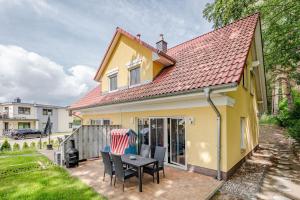 a yellow house with a table and chairs on a patio at Ferienhaus Kontraste 4m in Korswandt