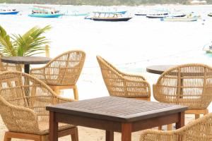 einen Tisch und Stühle am Strand mit Booten im Wasser in der Unterkunft Greywood in Gili Trawangan